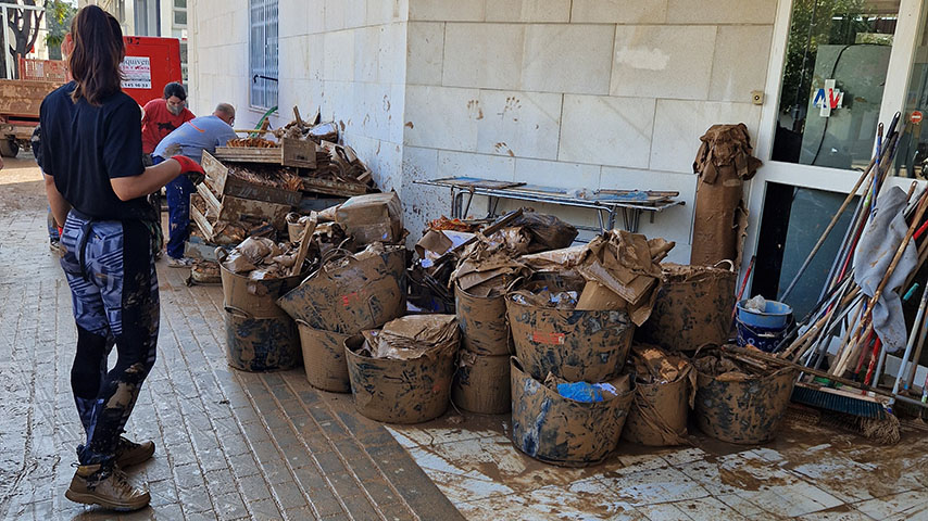 Una alumna junto a un montón de basura extraída de un sótano afectado por la DANA 